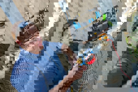 HVAC technician checking the pressure on an air conditioning unit