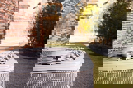 A residential central air conditioning unit sits on a lawn