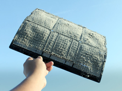 A hand holds a dirty air filter, covered in dust.