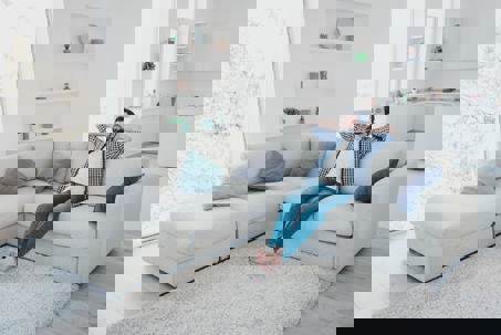 A man relaxes on a white sectional sofa.