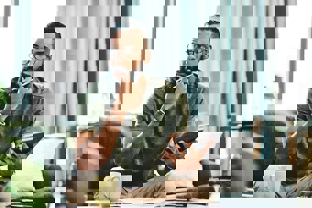 man sits on a couch, reviewing information on a tablet