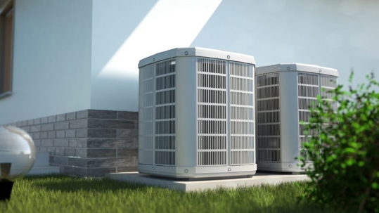 Two identical, new-looking, air conditioning units are outside of a modern home.