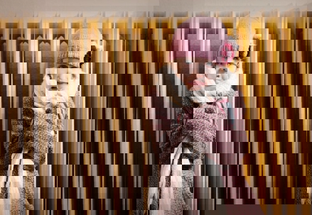 A young girl shivers in the cold, wearing a pink hat and scarf.