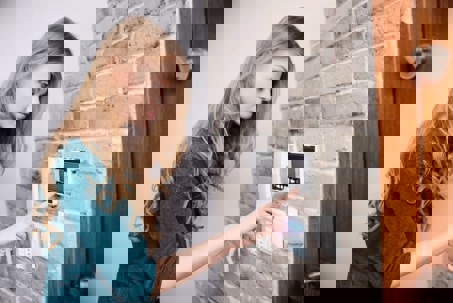 A woman uses a wall-mounted intercom system