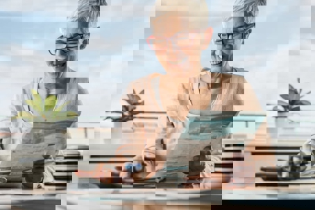 A smiling woman with glasses is reviewing paperwork, possibly related to home energy efficiency.