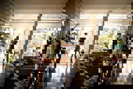 A couple looks out of a large window in their luxurious home