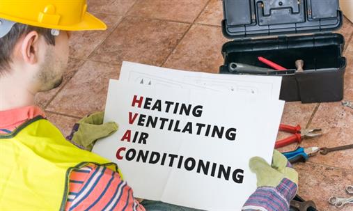 A HVAC technician holds a sign defining Heating, Ventilating, Air Conditioning.