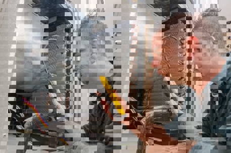 An HVAC technician inspects an air conditioning system.