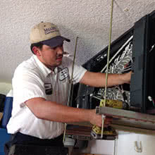 service tech working on a garage ceiling mount air handler