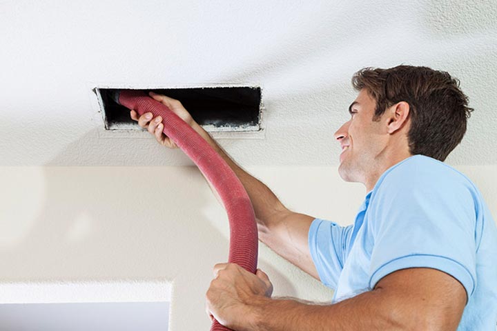 a man vacuuming out a ceiling duct